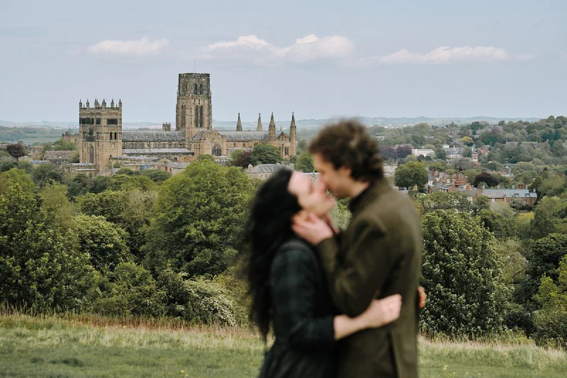 The engaged couple kissing above Durham city and cathedral