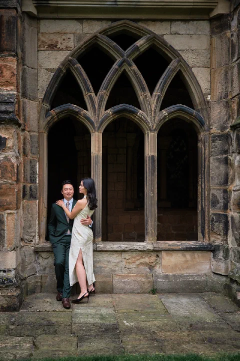 A newly engaged couple beside historic stone arches in Durham